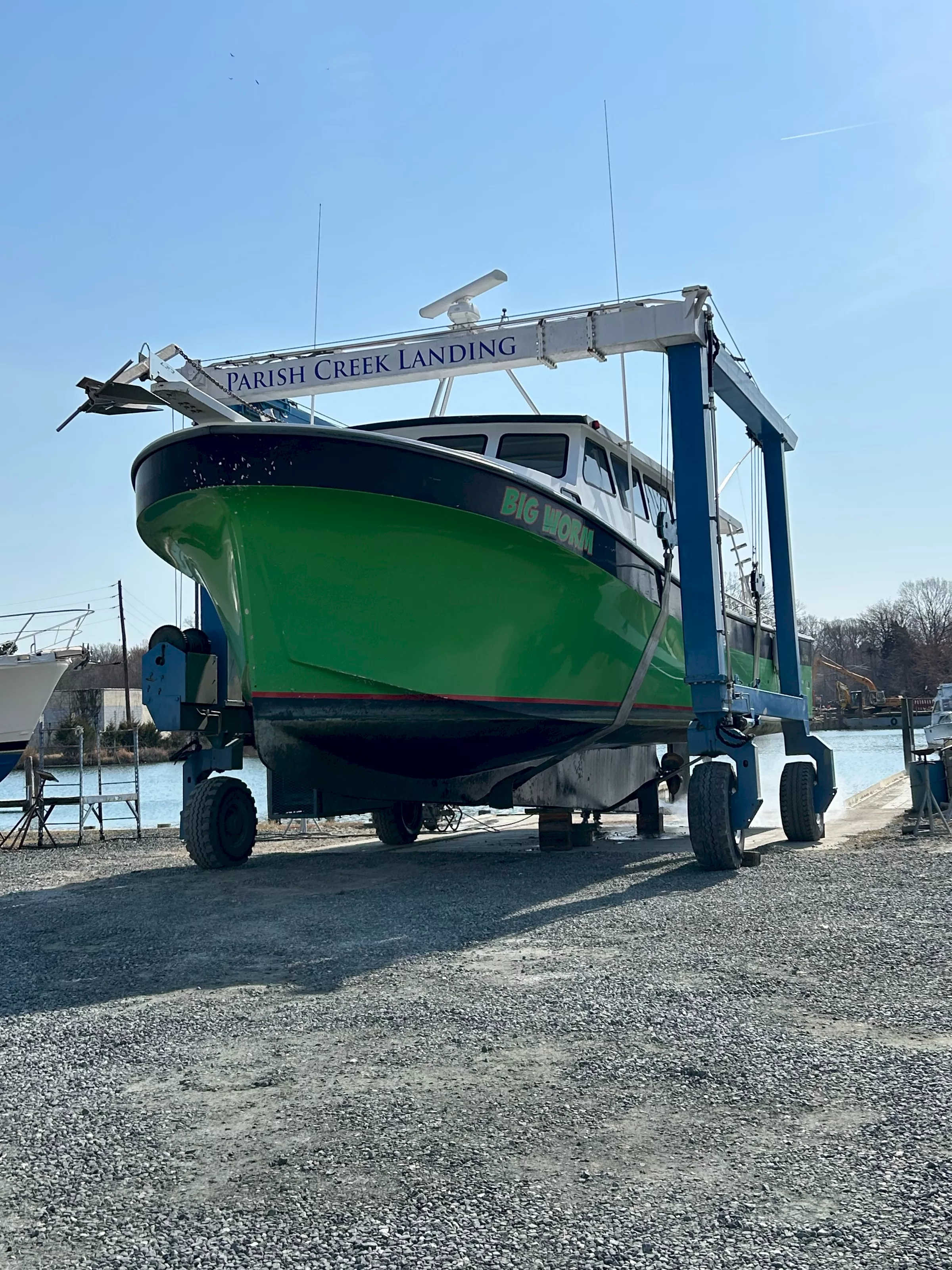 The green workboat Big Worm being pressure-washed in the travel lift
