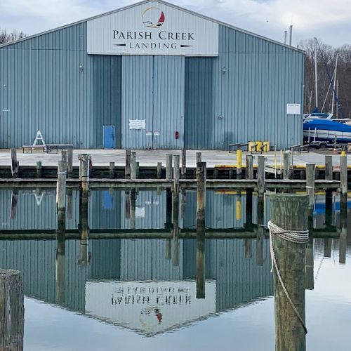 A warehouse-like building labeled Parish Creek Landing by the water, with docks, mooring posts, and boats nearby.