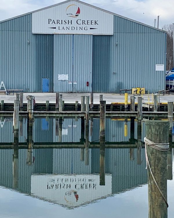 A warehouse-like building labeled Parish Creek Landing by the water, with docks, mooring posts, and boats nearby.