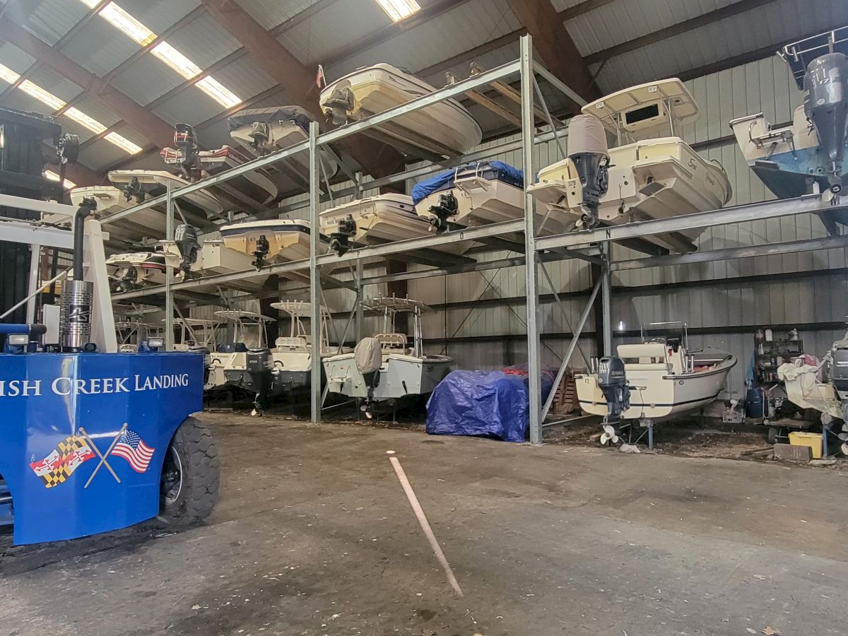A warehouse with multiple boats stored on racks. A blue vehicle labeled "Parish Creek Landing" is visible in the foreground.