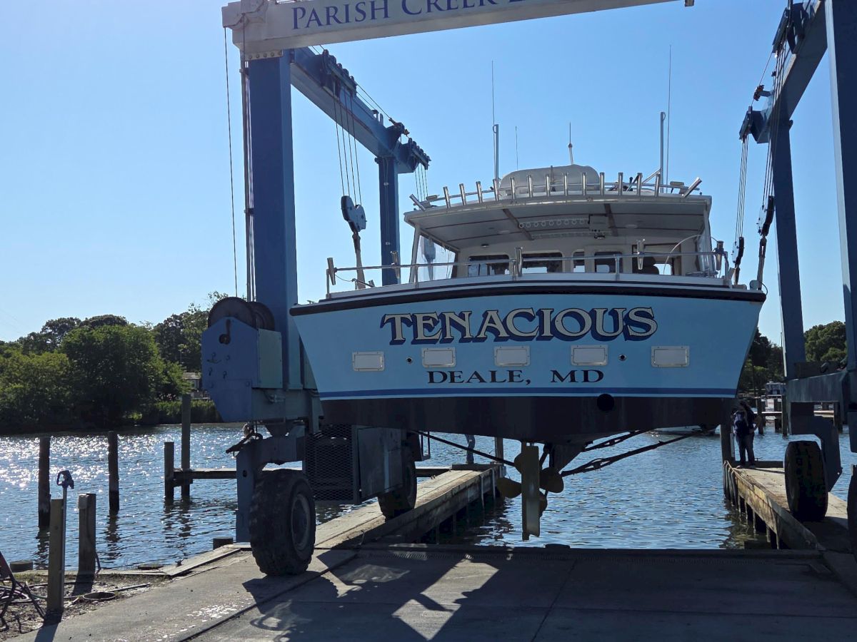 A boat named &ldquo;TENACIOUS&rdquo; is docked at Parish Creek Landing in Deale, Maryland under bright sunshine.